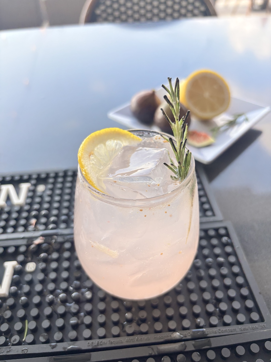 A botanical fig mocktail garnished with rosemary and lemon on the rooftop bar